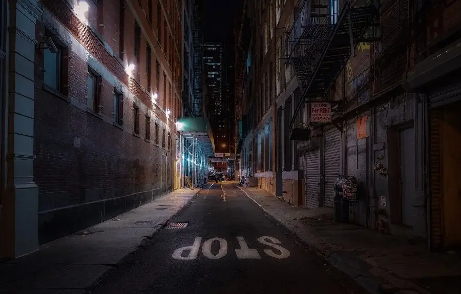 HD background of a small street with low light and the word stop on the ground of a city road