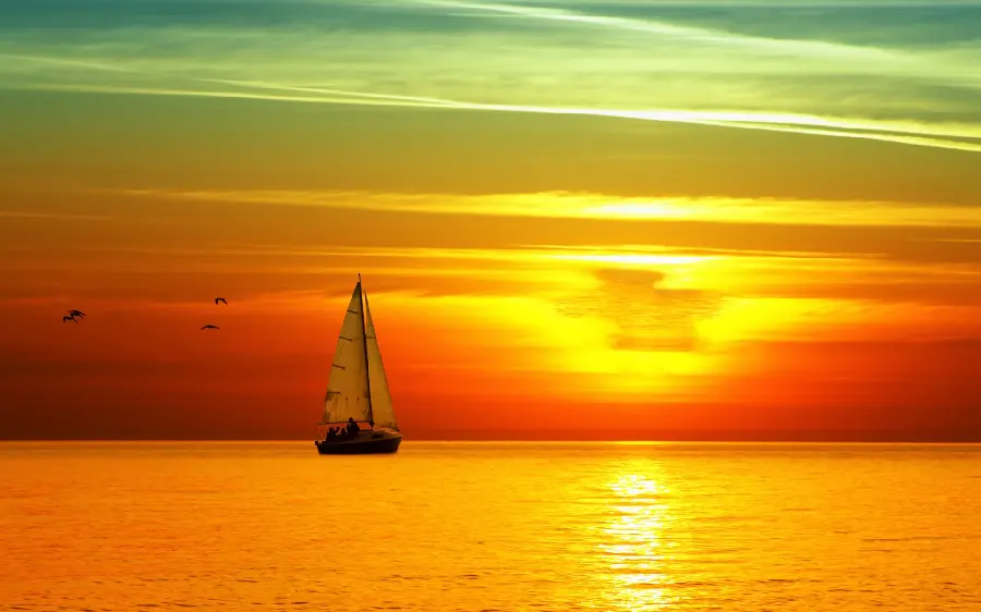 A special computer wallpaper of a golden sunset in the nature of the sea and a photo of its reflection in the water with a small sailboat