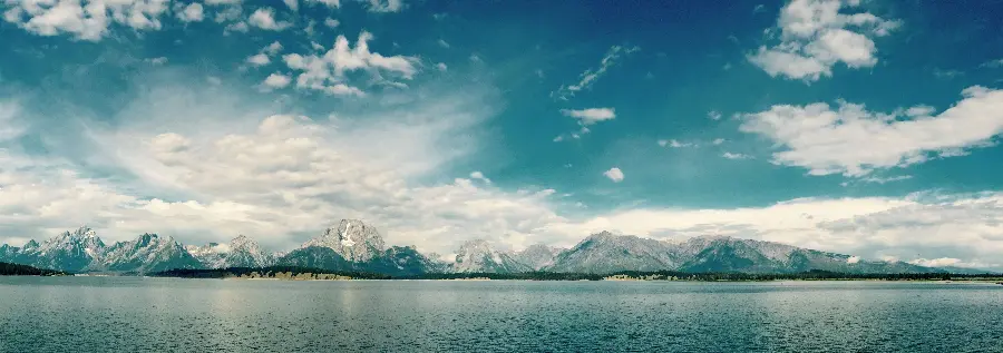 Download a strange background of a long ocean and continuous mountains with a cloudy sky