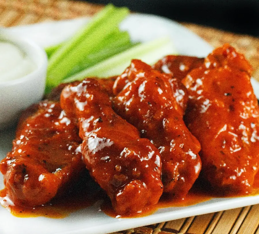 Top quality image of fiery chicken kebab dipped in a bright red sauce with celery stalks and white sauce suitable for mobile