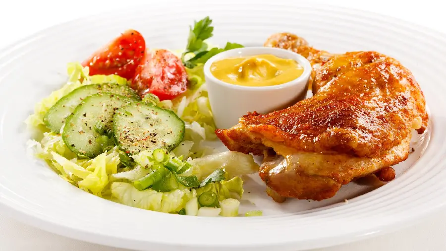 Download a high-quality photo From amazing chicken kebab with mustard sauce, salad consisting of lettuce, cucumber and tomato inA stylish dish