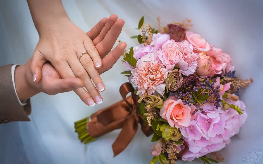 Download a romantic background image of a beautiful bouquet of flowers and the bride and groom holding hands