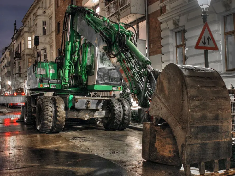Cool stock photo of a green excavator in the city