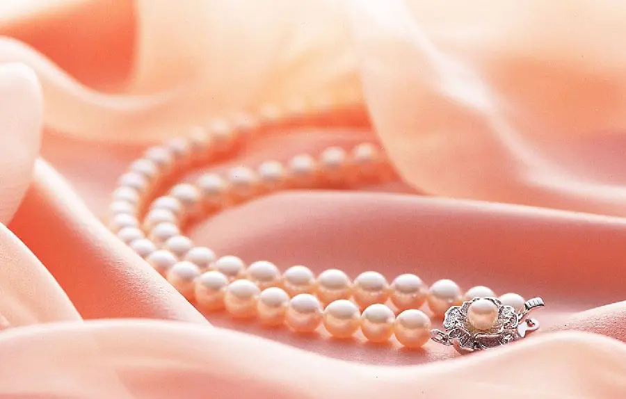 A very beautiful background photo of a pearl necklace on a pink lining