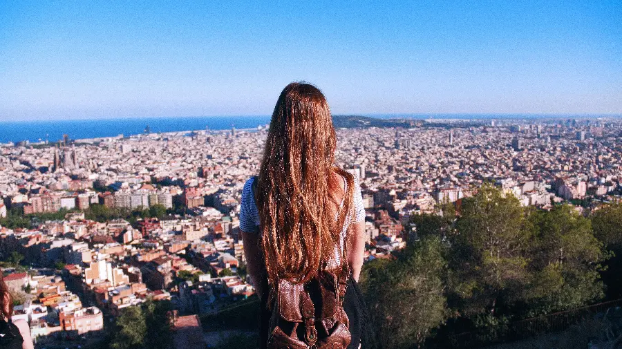 Picture of a cute brown-haired girl with a backpack looking at the sights of Barcelona