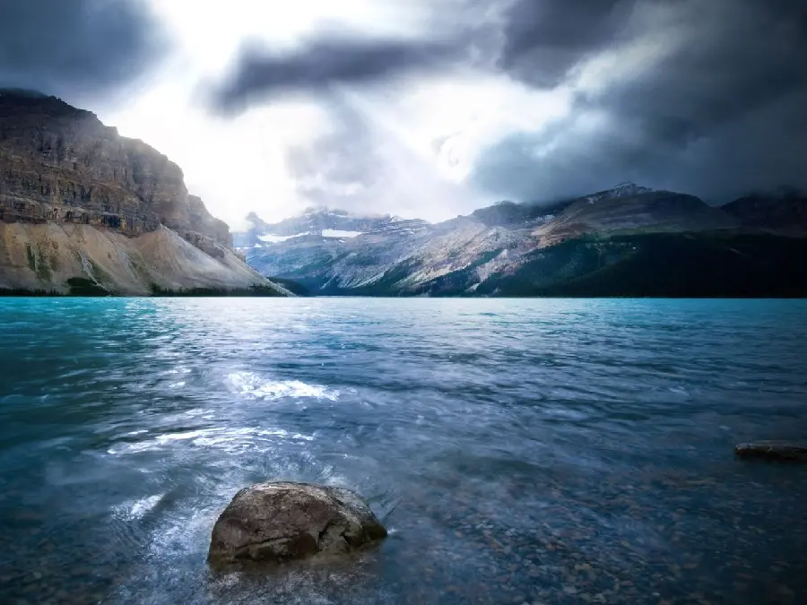 A high quality background of the clear ocean and the rocks in it and the mountains next to it and the clouds Dark sky