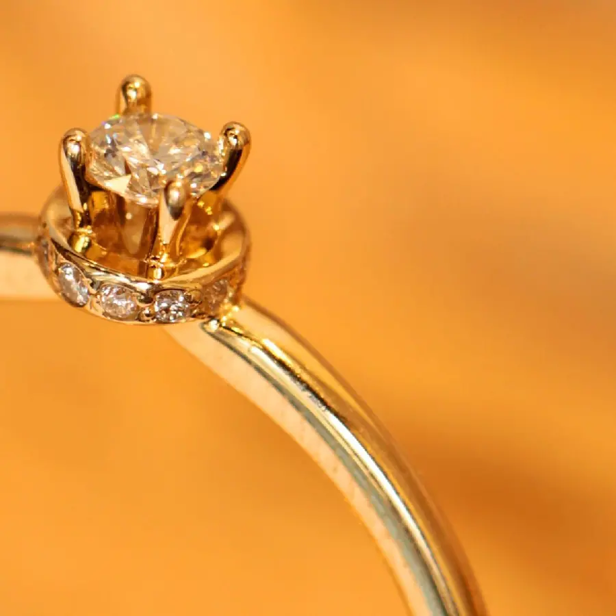 Half and half photo of a gold diamond ring on an orange background