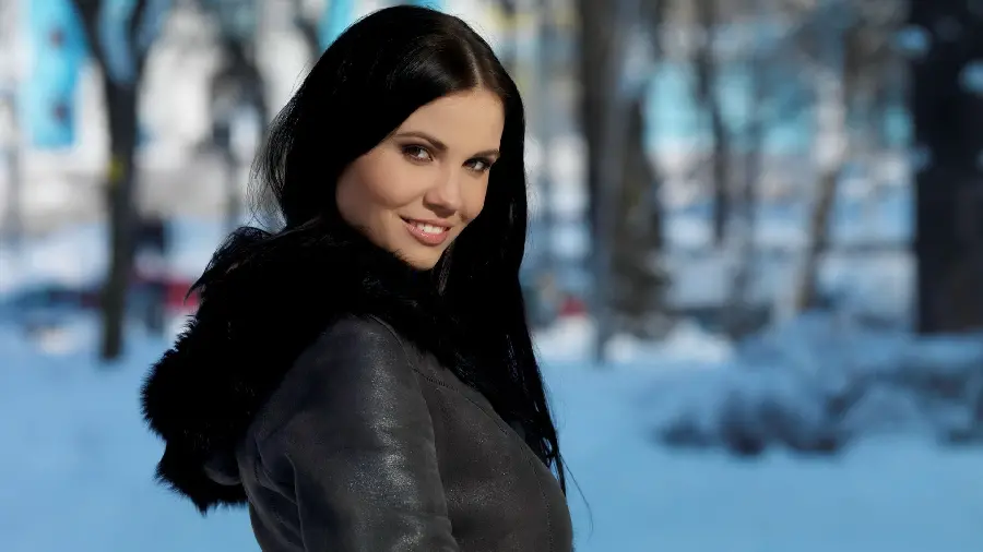 Stock and shiny image of a smiling girl with black hair and a black coat in snowy weather, special laptop profile