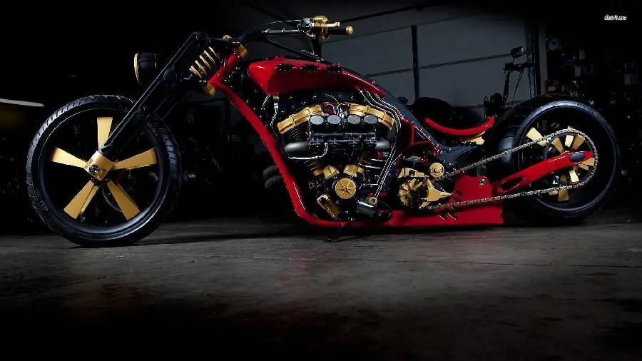 Download a stock photo of a new and heavy custom motorcycle with three colors of gold and red and black on a dark background