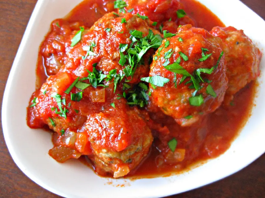 The most special background of a fresh Kofte dish mixed with a special red sauce and garnished with chopped vegetables on a white circular plate suitable for WhatsApp