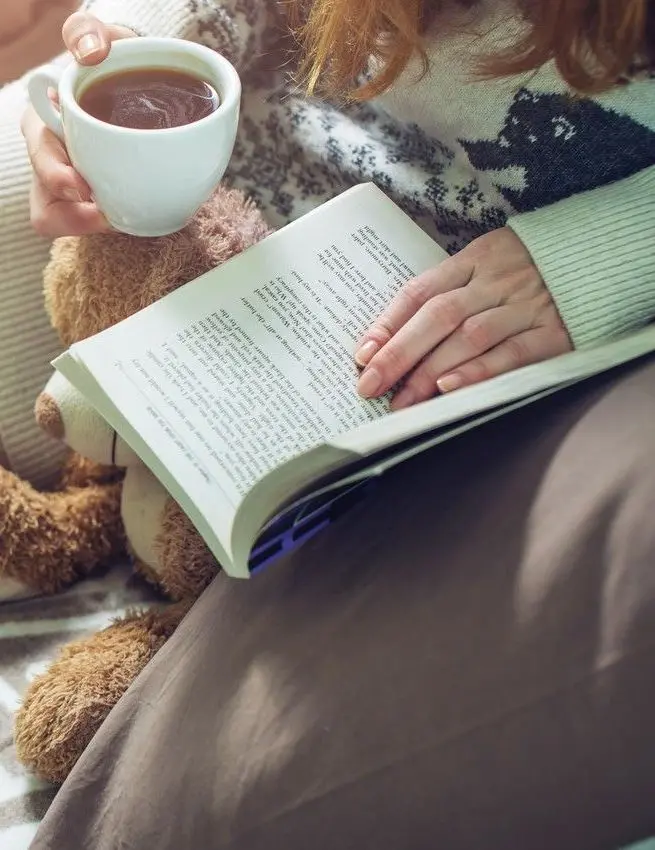 Artistic image of a girl reading a book and drinking tea