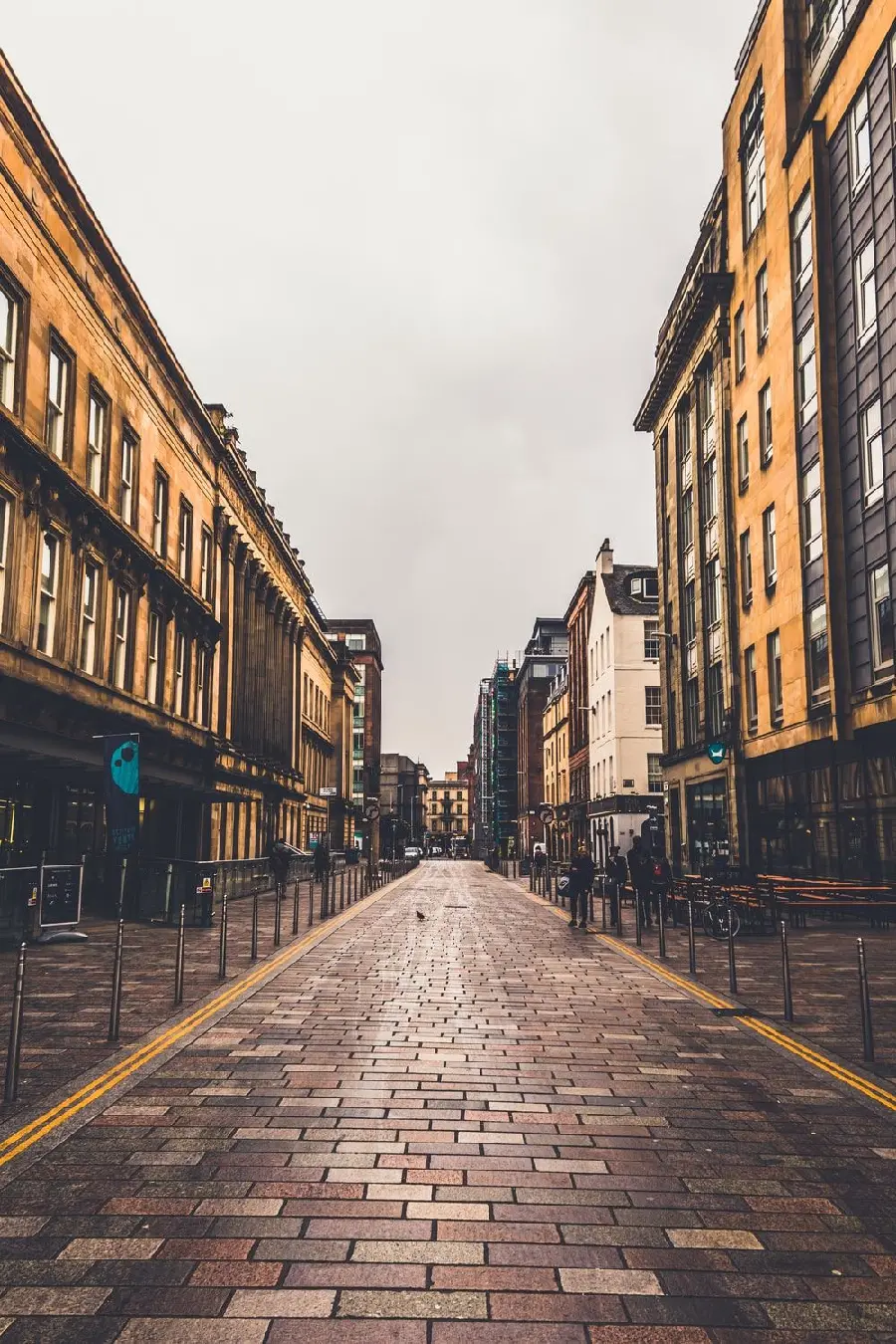 Download a unique image of burnt brown and cream facades with iron railings on both sides of a brick-shaped city road