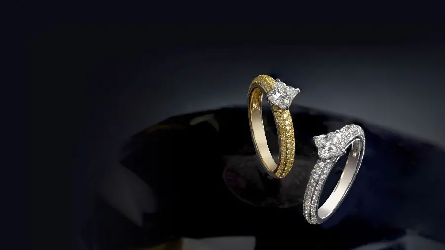 Black background of two gold and white diamond rings with many gems