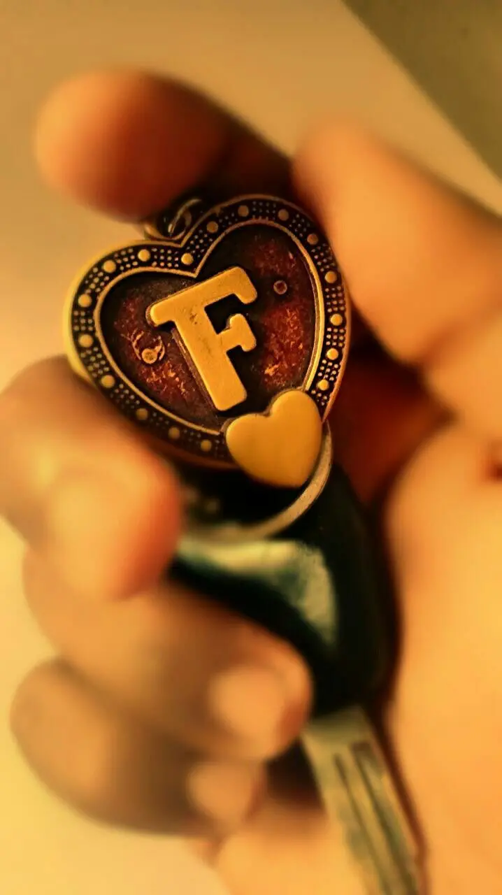 Cute background of a beautiful heart-shaped F in a small hand