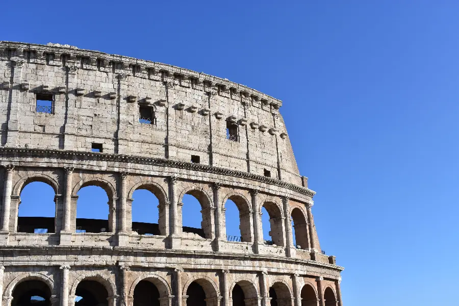 A stock photo of the Colosseum that is incomplete due to the passage of time with a clear blue sky