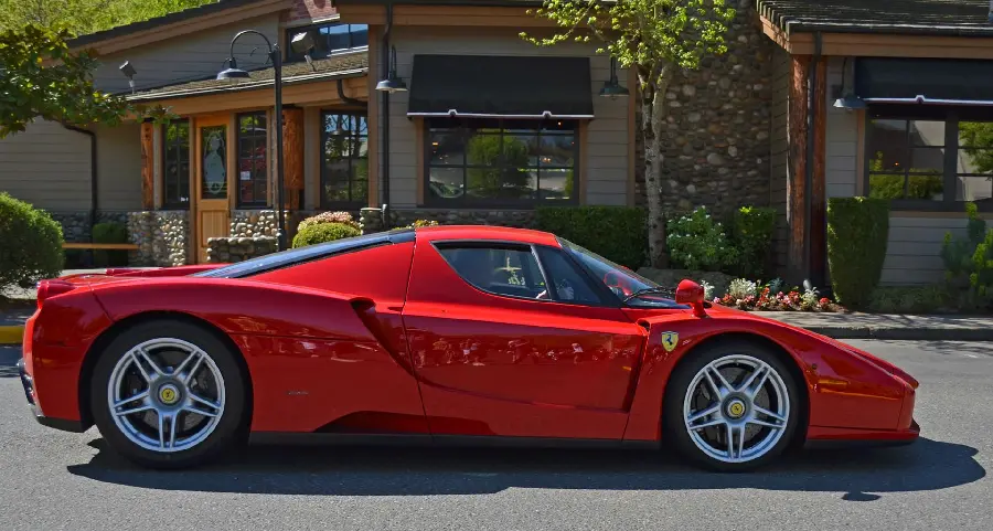 Photo of the shiny background of the Ferrari Enzo from the right side in front of a beautiful building