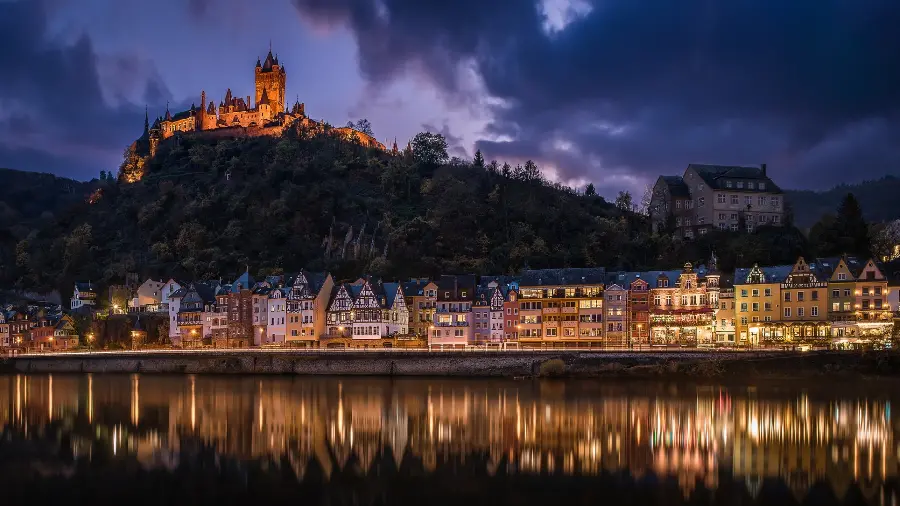 A brilliant image of a regular urban nature by a river and houses on a hill and a dark landscape photo of scattered clouds