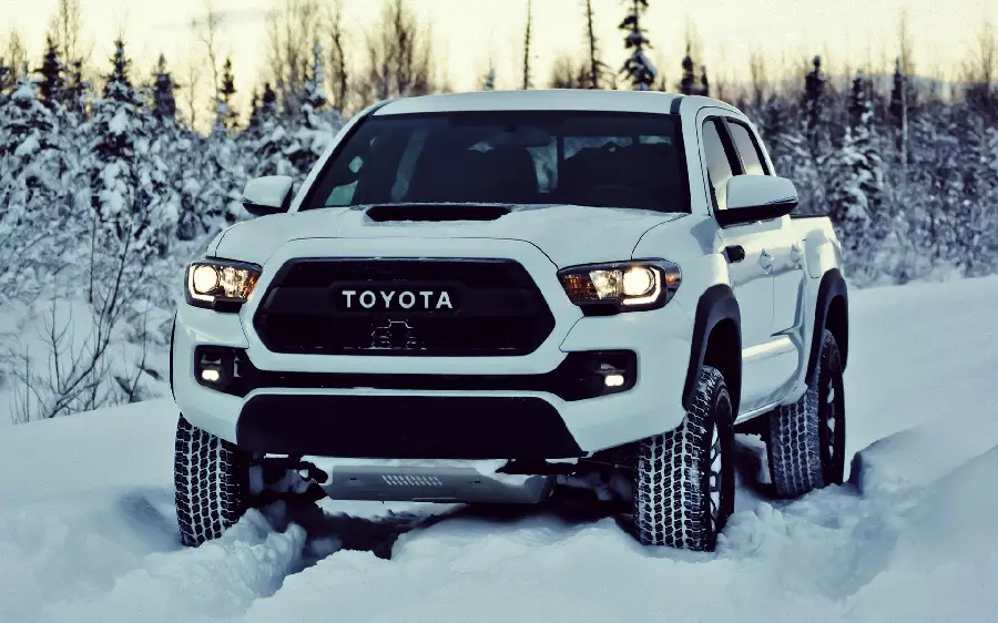 Download a background image with a youthful design of a white Toyota Tacoma on a snow-covered ground