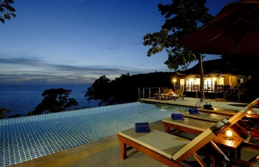 A special relaxing tablet background photo of sun loungers Poolside and Beach House Illuminated at Night