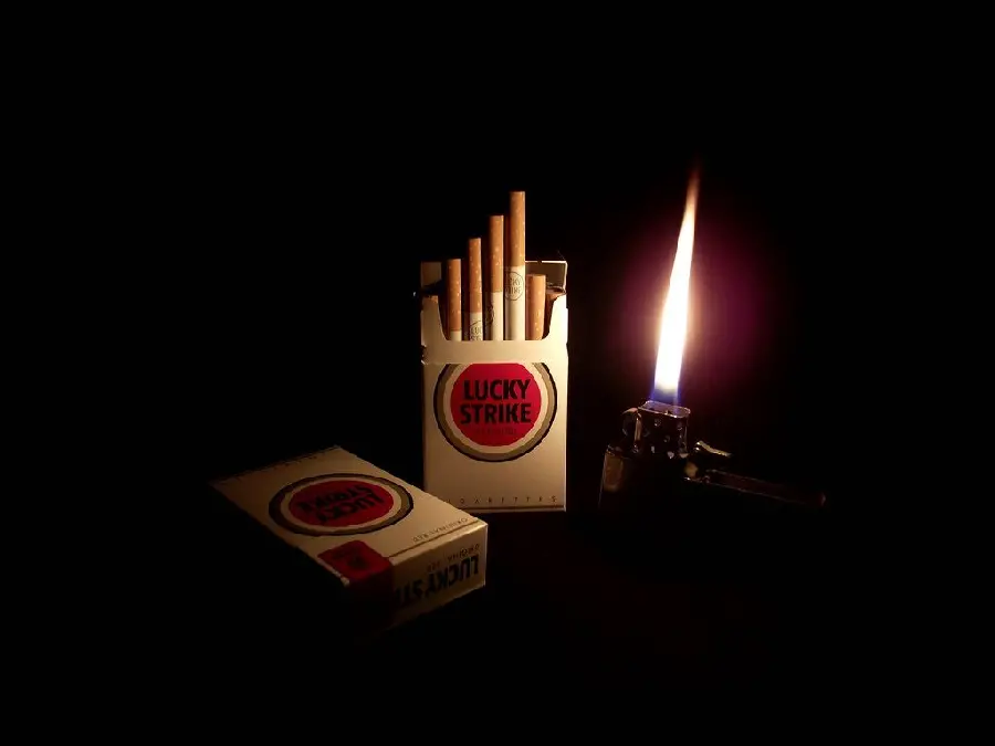 A silent background photo of 2 packsMarlboro cigarettes, one open and one closed, next to a lit lighter