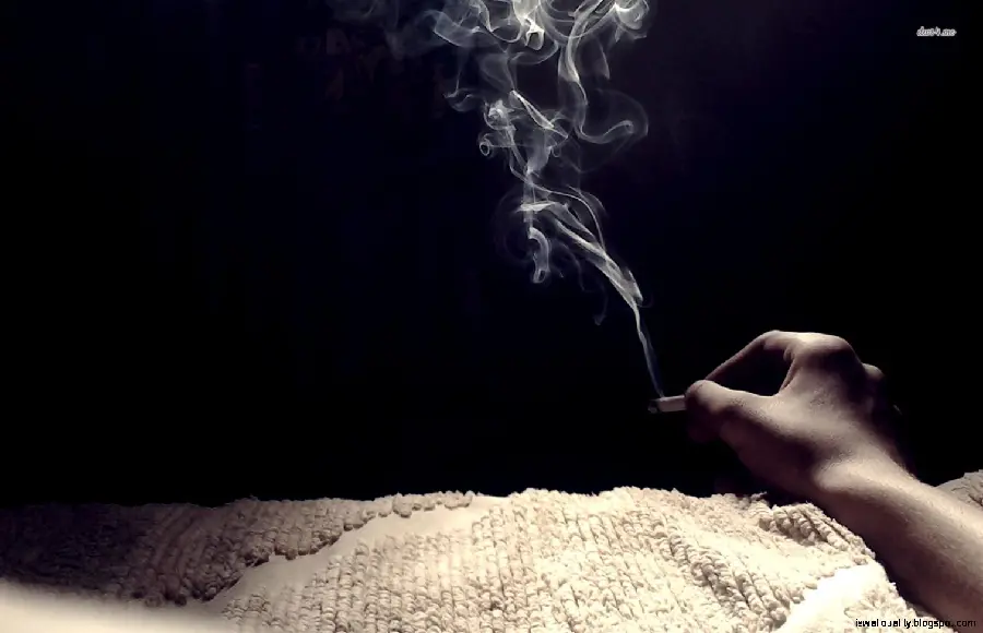 Download a special dark background photo of a tablet with white cigarette smoke in a hand next to a cigarette