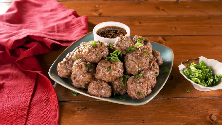 A high-quality background image of Greek meatballs, the best food, decorated with onions and soy sauce, suitable for laptops