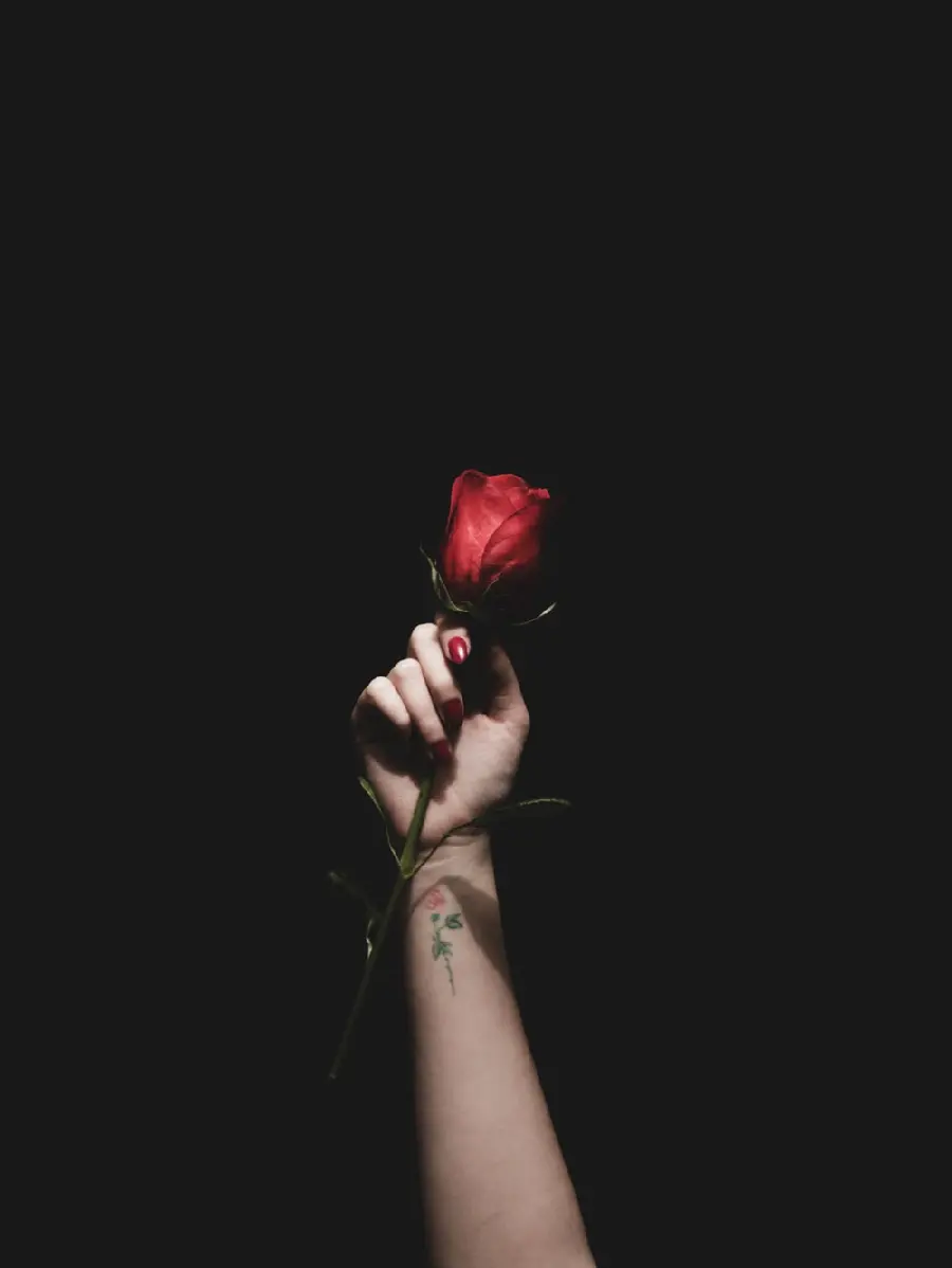 Download black background of a rose in a hand with a rose tattoo