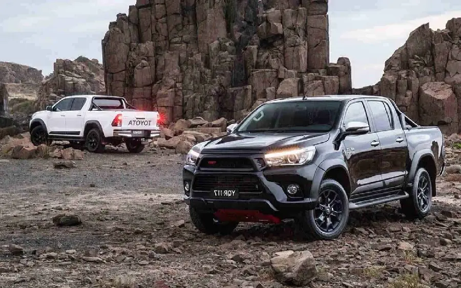 The latest high-quality poster of a pristine white and black Toyota Hilux in Opposite direction also next to the rocks for Windows
