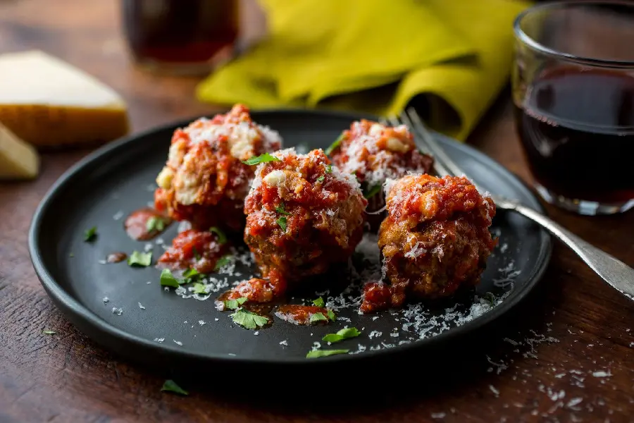 Download the hottest background photo of modern meatball food with red sauce decoration and some vegetables on a black plate
