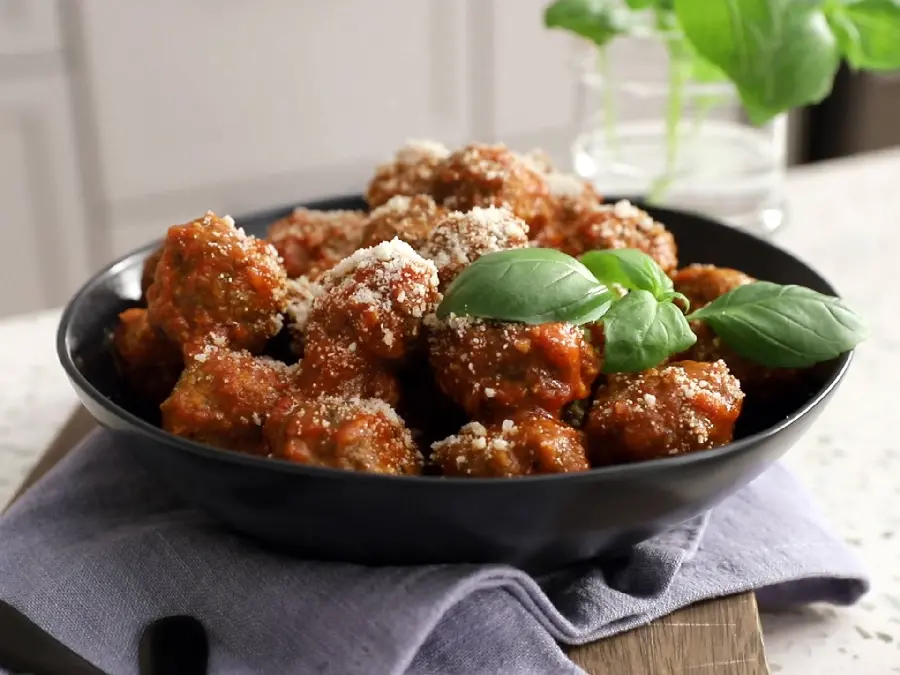 Beautiful and classy background photo of meatballs of the same size, food in a black dish with sauce garnish and a small mint plant