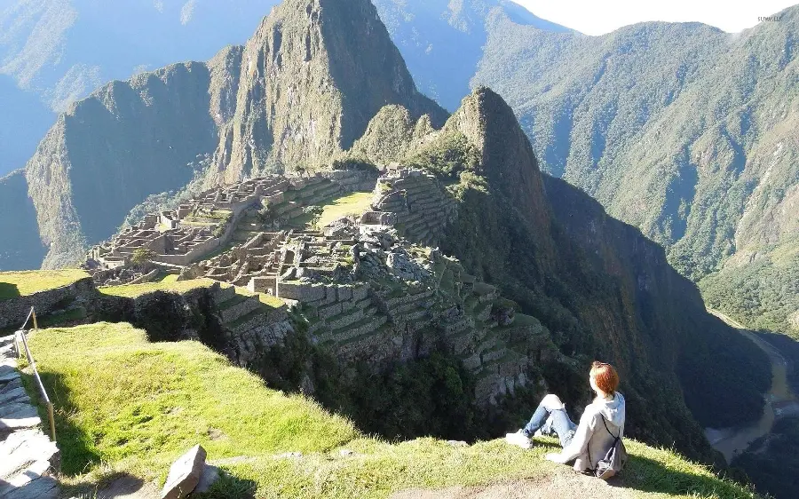 Amazing image of a tourist girl sitting looking at the amazing view of Machu Picchu