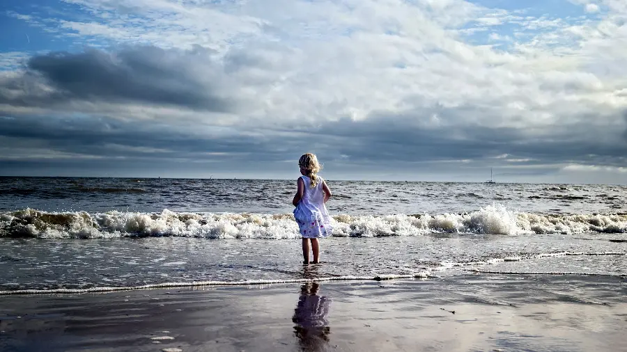 Beautiful wallpaper of a golden-haired girl on the beach in a purple dress 