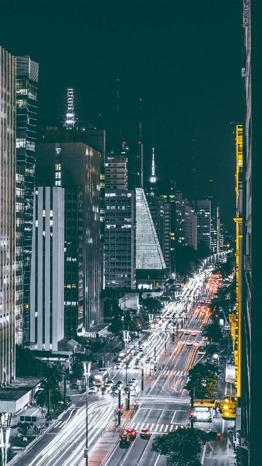 Download a famous, majestic and illuminated poster of a modern city road at night and public transport passing by