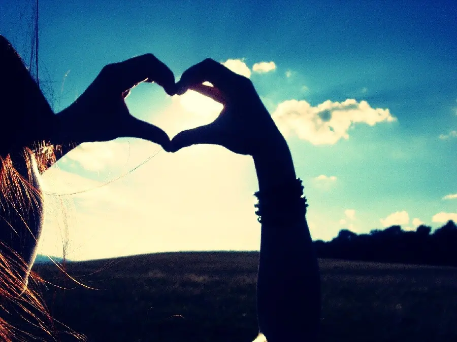 Interesting profile of a heart with a girl's hand in a beautiful blue and cloudy sky