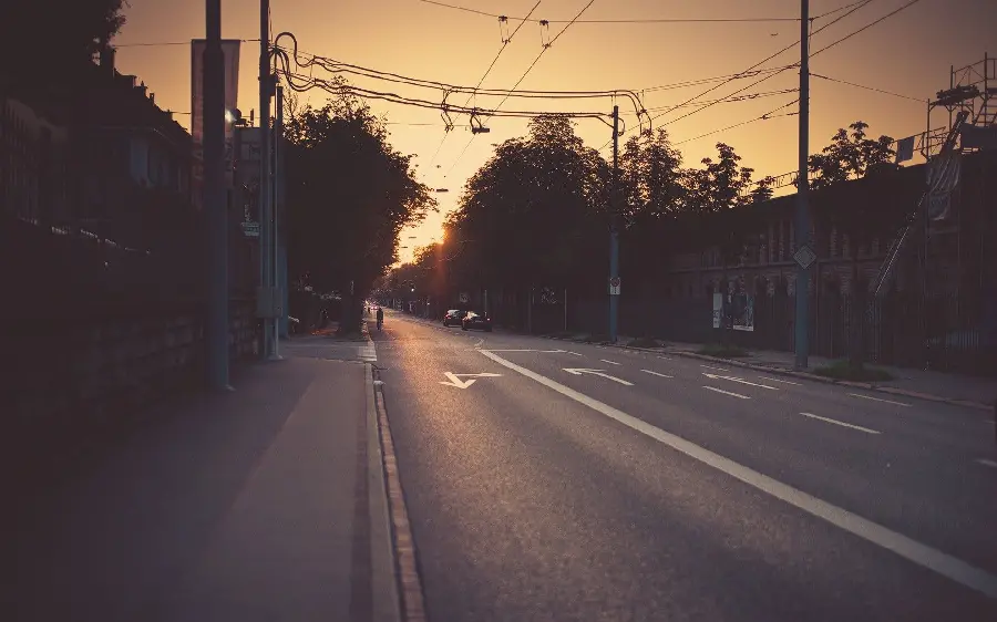 A gloomy and miserable stock image of a bad urban road with trees and power lines