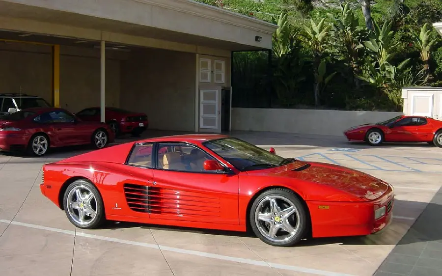 Download a stylish background image of a classic old red Ferrari in front of the sun in the parking lot