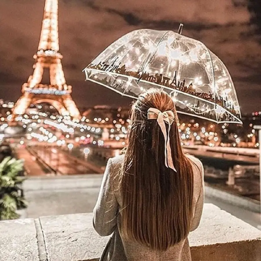 Amazing picture of a long-haired girl watching the Eiffel Tower with an umbrella