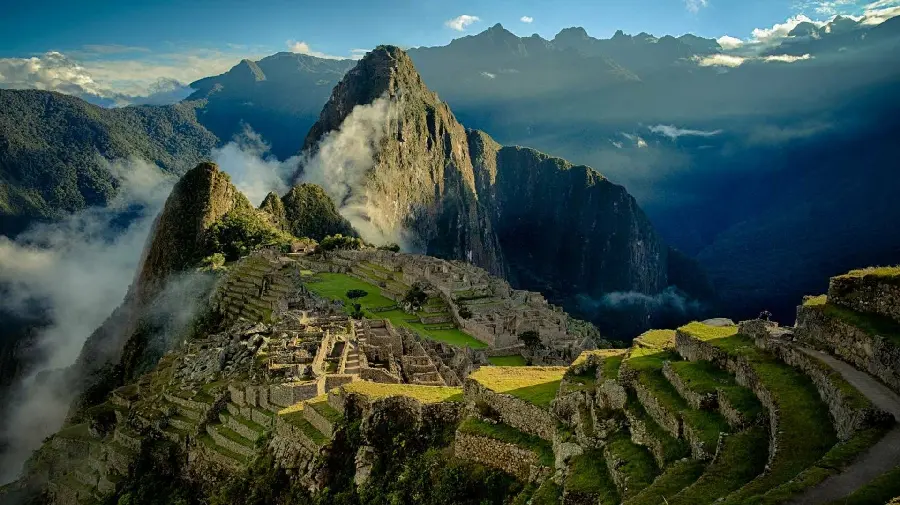 Download the captivating image of Machu Picchu hidden among the mountains and vegetation