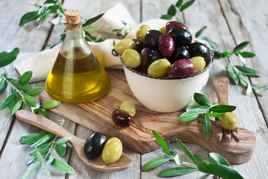Download colorful profile picture of a bowl of olives with a small bottle of oil and a spoon with 2 olives and leaves around it