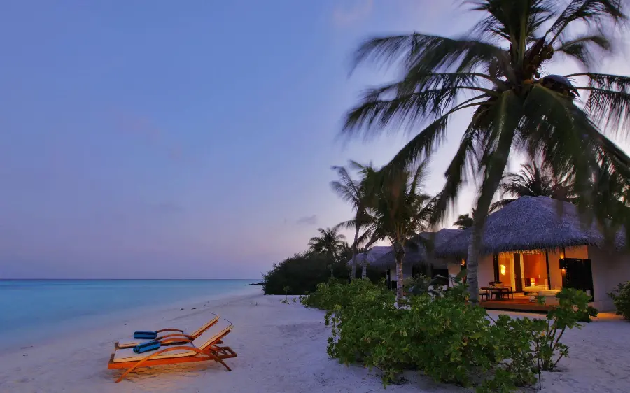 Download dark and light image of a beach house villa with sun loungers and a beach house by the beach of an island in high quality