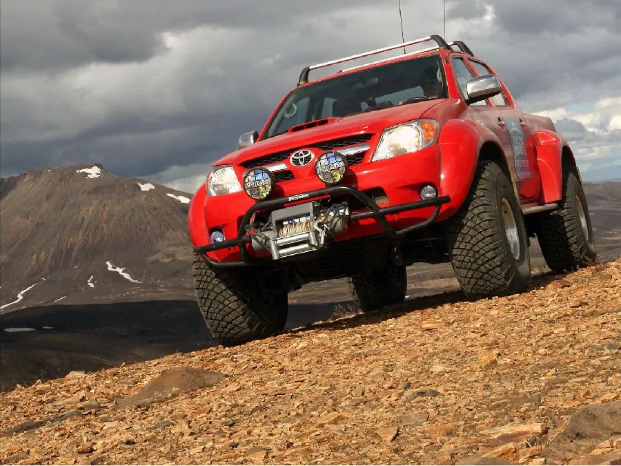 Best Stock Photo of Stunning Red Toyota Hilux on Mountain Road with Black Cloudy Sky