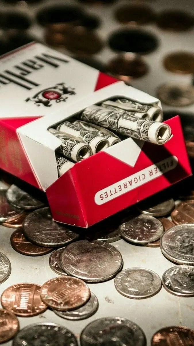 Luxurious fantasy image of tangled dollar threads in a Marlboro cigarette box and countless coins around it