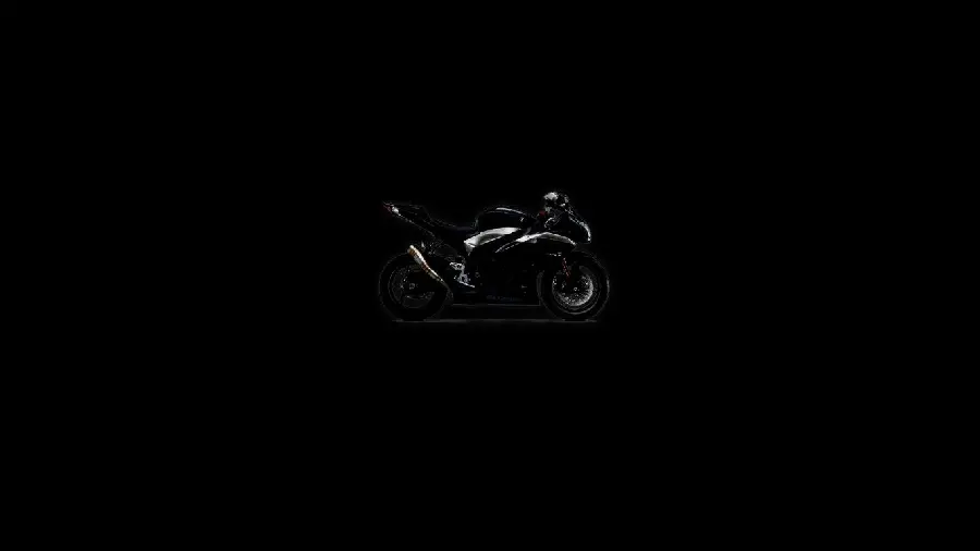 A black background from a very far view of a motorcycle in poor quality