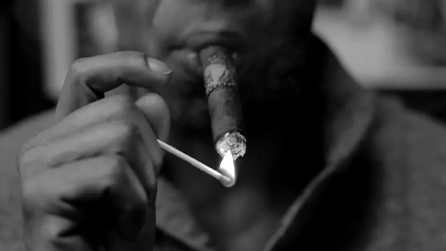 Download Image of a Black Man Lighting a Cigarette with a Match and Smoking it