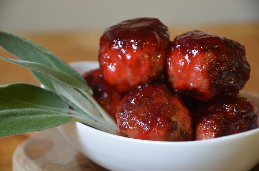 Download the hottest stock image of meatballs with a delicious red sauce and green herbs next to a white bowl