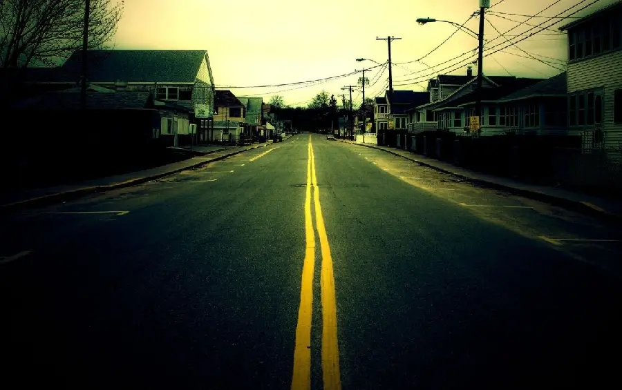 Abandoned photo of houses and power cables on both sides of a city road with a yellow line in between