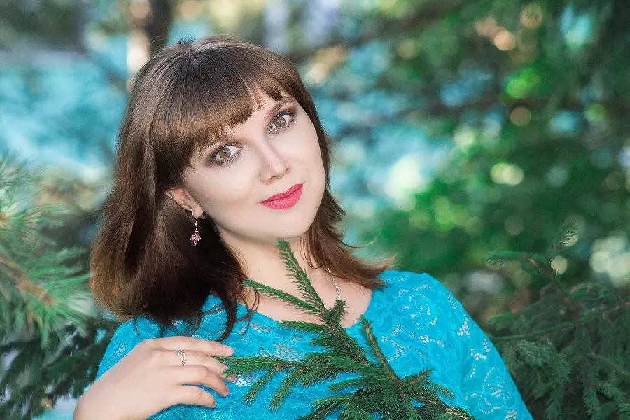 Beautiful wallpaper of a cute girl with brown eyes and hair and a blue lace dress next to green leaves