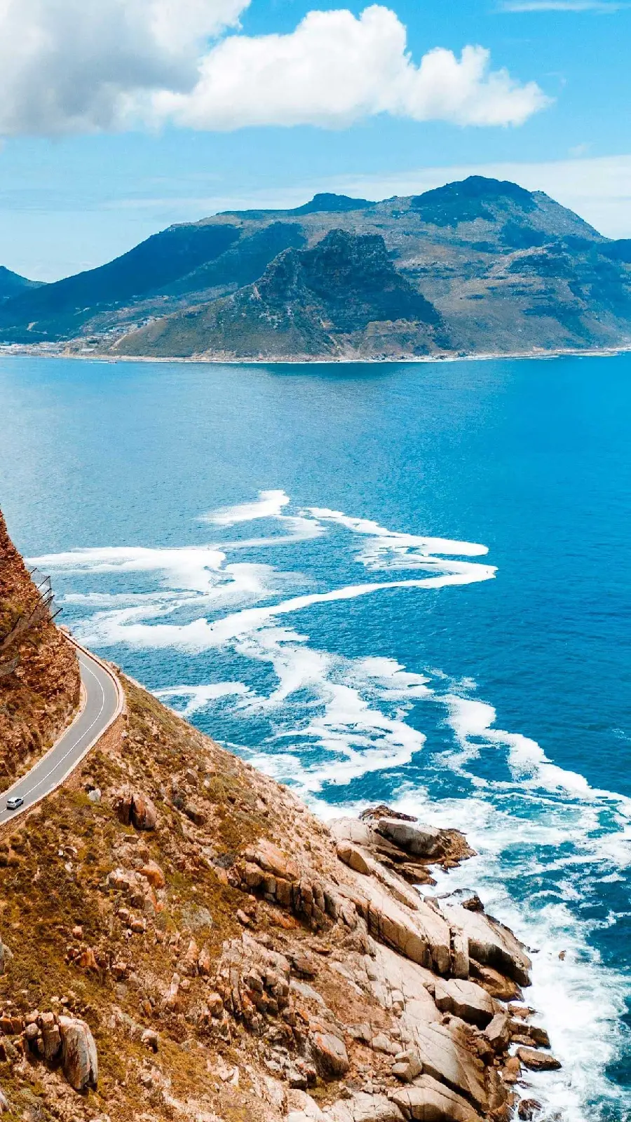 Download a sensational stock image of the ocean and a mountain road and mountains in the same color as the ocean in hd quality
