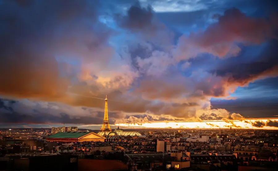 Wallpaper of a distant view of the city of Paris, France and a symbol of culture at night with dark clouds