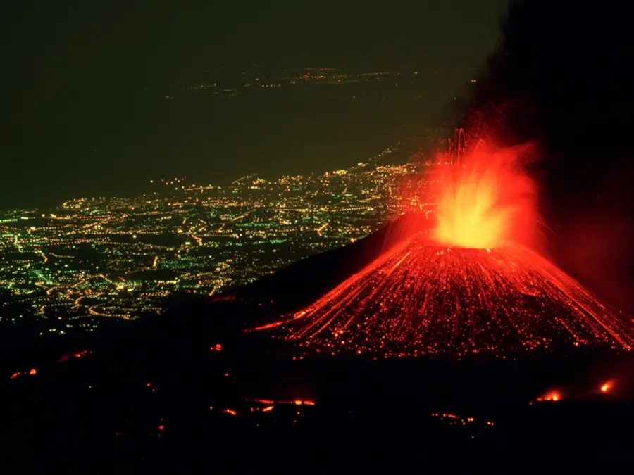 City view at night from the eruption of an orange active volcano